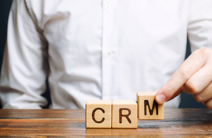 Wooden blocks with the word CRM (Customer Relationship Management) and businessman